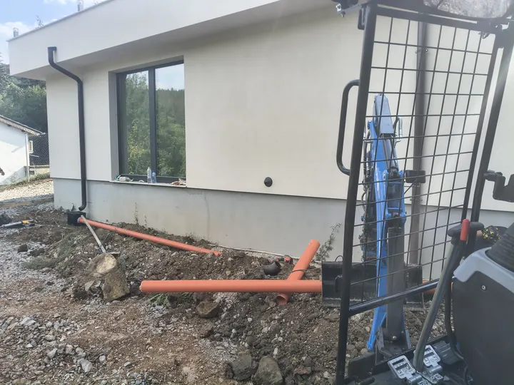 Оранжеви дренажни тръби до фасада след изкоп с минибагер