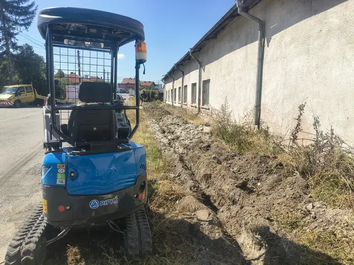 Минибагер Rippa R15 — канал покрай сграда